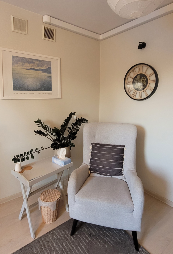 Zdjęcie gabinetu z szarym wygodnym fotelem i stolikiem z dekoracjami